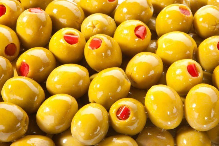 Close-up van een schaal met groene olijven gevuld met rode paprika, ideaal voor een mediterraans aperitief