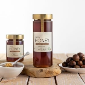 Een glazen pot Griekse kastanjehoning, met een kom honing en verse kastanjes op een houten ondergrond