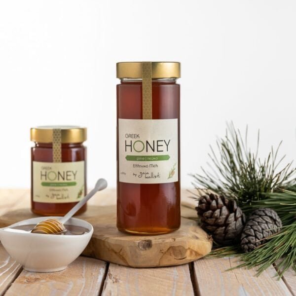 Een glazen pot met Griekse pijnboomhoning, met een witte kom honing en dennenappels op een houten ondergrond